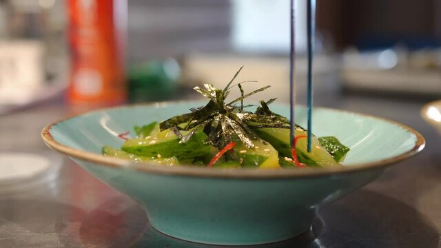 Apprentice cook chef kitchen practicing beautiful presentation dishes visitors cafe. Tweezers add herbs to the salad in detail. Cooking as an art. The aesthetic design of the dish in the restaurant.