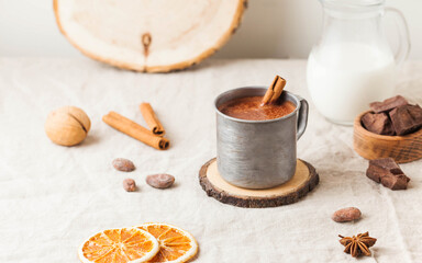 Fototapeta na wymiar Hot chocolate in a metal mug with a cinnamon stick on the tablecloth. Copy space