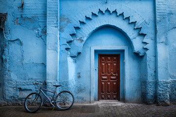 Fototapeta na wymiar Traditional Moroccan ancient wooden entry door. In the old Medina in Chefchaouen, Morocco. Typical, old, blue intricately carved, studded, Moroccan riad door.