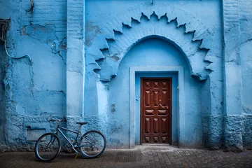 Zelfklevend Fotobehang Traditional Moroccan ancient wooden entry door. In the old Medina in Chefchaouen, Morocco. Typical, old, blue intricately carved, studded, Moroccan riad door. © mitzo_bs