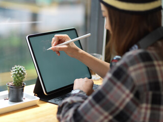 Female teenager drawing on mock up digital tablet in cafe