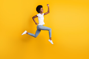 Full length body size photo of funny pretty female hipster with black skin jumping high running fast screaming loudly isolated on bright yellow color background