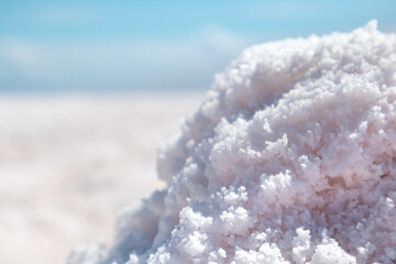 Pink salt textured macro shining on coast of salt lake with blurred blue sky background. Spa...