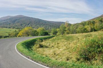 Obraz premium Bieszczady National Park. Curvy asphalt road. Idyllic autumn hills landscape. Travelling through southern Poland. Green meadow mountains background.