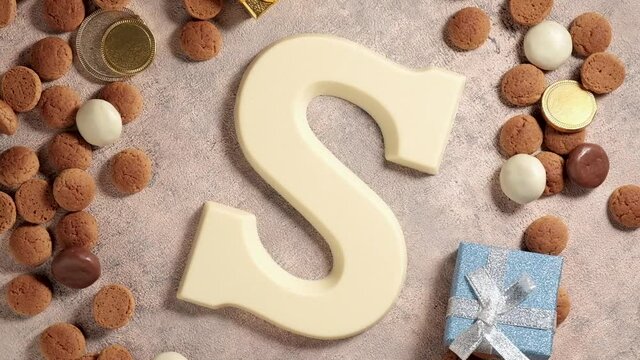 Rotation of kruidnoten, traditional sweets, strooigoed and white chocolate letter S. Background for Dutch holiday Sinterklaas. St. Nicholas day concept. FullHD video, top view