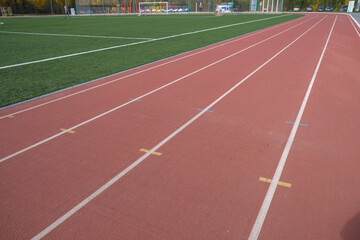 Red treadmill going into the distance. Against the background of green grass.