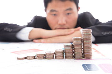 Asian male staring at a row of increasing dollar coins on the table