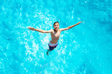 View from above of the boy falls in the water stretch hands jump diving in pool