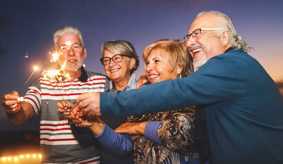 Happy senior family celebrating with sparkler fireworks at home party - Elderly people lifestyle...