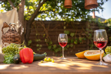 Two glasses of red wine on table with fruit and vegetables