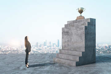 Young businesswoman looking on concrete stairs with gold winners cup