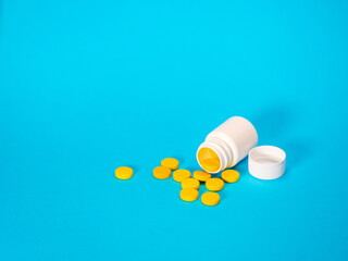 Yellow pills and plastic white bottle. Blue background with copy space for text. Healthy and medicine. Pain management. Drug abuse in teenage concept