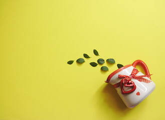 a decanter with a heart shaped candy and green leaves on yellow background