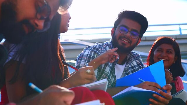 indian friends sitting on stairs outdoors with copybooks