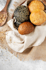 Fototapeta na wymiar Sesame buns for burgers. Wheat and rye buns in a basket on a light gray background. Homemade buns with sesame seeds. Top view. Copyspace