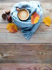 Autumn leaves, cup of coffee and warm scarf on wooden table. Fall season, leisure time, Sunday relaxing, coffee break and still life concept. Selective focus. Top view, copy space.