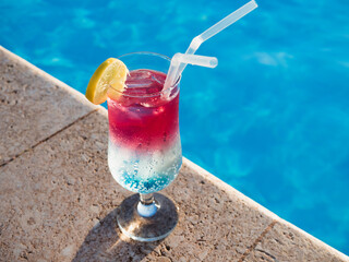 Beautiful glass with a cocktail on the background of the pool. View from above, close-up. Concept of leisure and travel