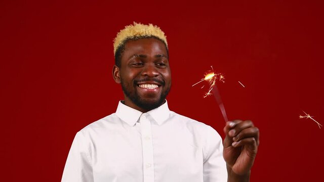 african american man holding a burning stick of dynamite in studio red background