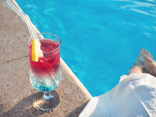 Beautiful glass with a cocktail on the background of the pool. View from above, close-up. Concept of leisure and travel