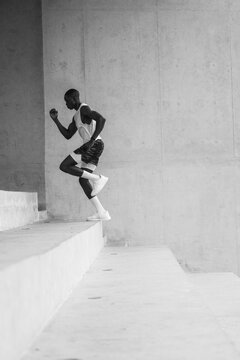 Side view of young man exercising on steps outside building