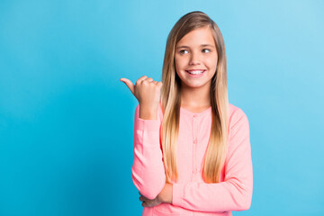 Photo portrait of girl pointing finger thumb looking at blank space isolated on pastel blue colored background