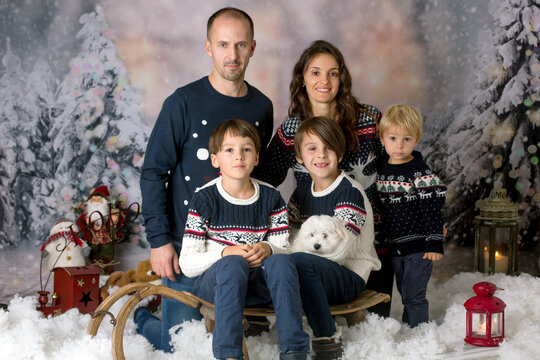 Happy family, parents with three children and puppy dog, having christmas pictures taken