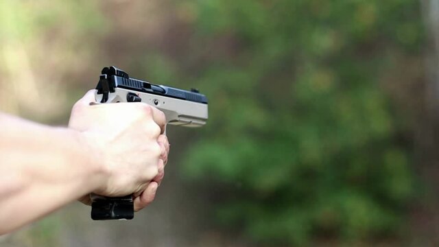 shooter shoots a pistol at slow mo, case release, soft focus