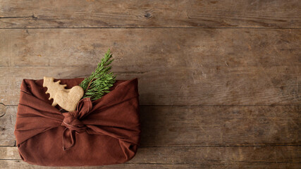 Christmas gift packed furoshiki lie on a brown wooden table. zero waste concept