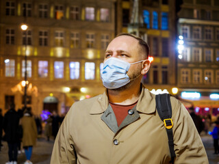 Adult man wearing mask walking in a night european city. Mask is a necessary thing in new normal...