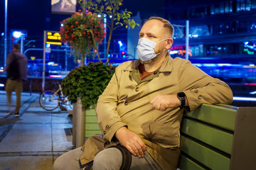 Adult man wearing mask walking in a night european city. Mask is a necessary thing in new normal...