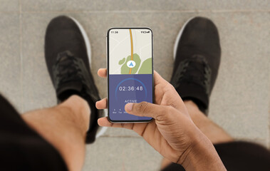 Urban training and route or navigation for jogging. Man athlete looks at smartphone with GPS map...