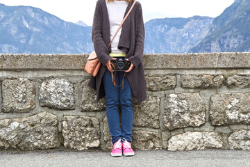Young caucasian woman holding vintage retro camera outdoors.