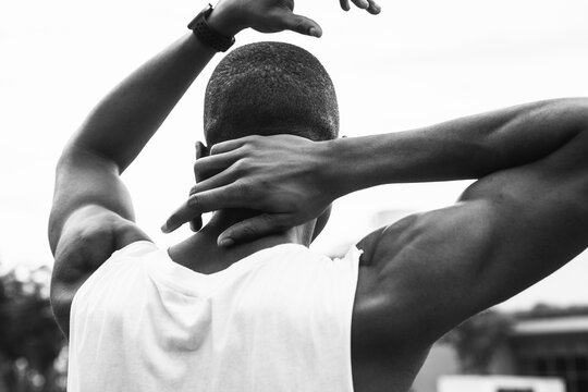 Rear view of young man performing neck exercise on street against sky