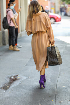 September 24, 2020: model wears a pair of purple heeled ankle boots and a brown overcoat