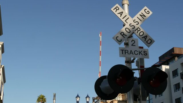 Level crossing warning signal in USA. Crossbuck notice and red traffic light on rail road intersection in California. Railway transportation safety symbol. Caution sign about hazard and train track.