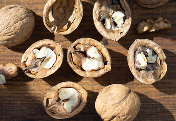 Walnuts in shells lie on a wooden surface