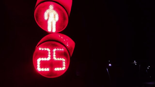 A red light came on at a pedestrian traffic light. No pedestrian traffic for 30 seconds with a countdown display. Night shooting.
