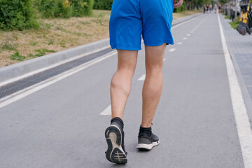 Handsome man jogging in the park. Sportsman runs exercising training outdoors.