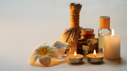 Beautiful spa composition with candles, frangipani flower, oil flasks, bowl with salt and herbal...