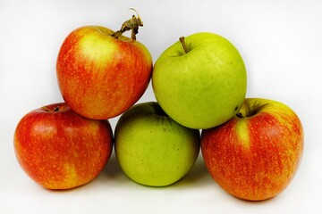 Ripe red and green apples lie on a white table