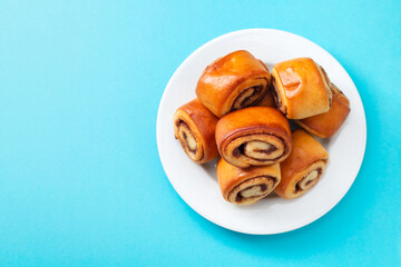 buns with cinnamon on white plate on blue background
