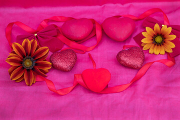 Plakat Red hearts, bows, ribbon and flowers lie on a red background.