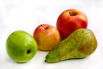 Three apples of different sizes and colors and a green ripe pear on a white background