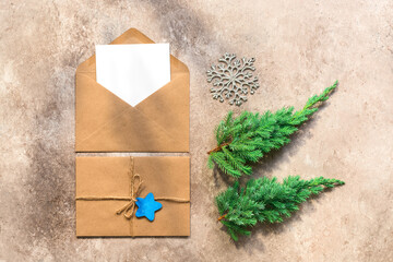 Mockup of a Christmas or New Year card. Blank paper card in a brown envelope, letter and fir branches in the sunlight with shadows on a beige rustic background. Template for your design. Top view