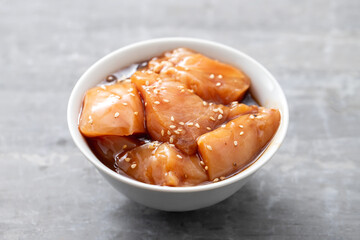 raw chicken with sauce and sesame in white bowl