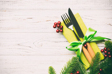 Top view of christmas decorations on wooden background. Fork and knife on napkin tied up with ribbon and empty space for your design. New year pattern concept