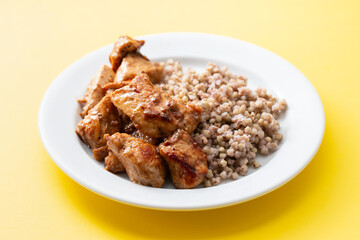 boiled buchwheat with chicken in sauce on white plate