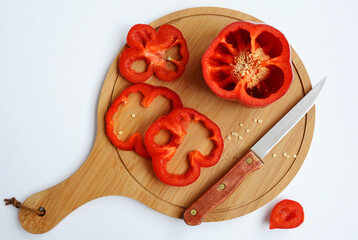 Red bell pepper and knife lie on a cutting board