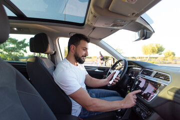 Bearded man driving suv car and looking smartphone programming vehicle