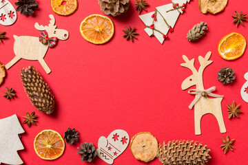 Top view of red background decorated with festive toys and Christmas symbols reindeers and New Year trees. Holiday concept with copy space